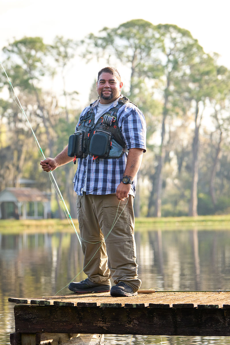 Wounded Warrior Tim Aponte smiling while holding a fishing pole at the lake.