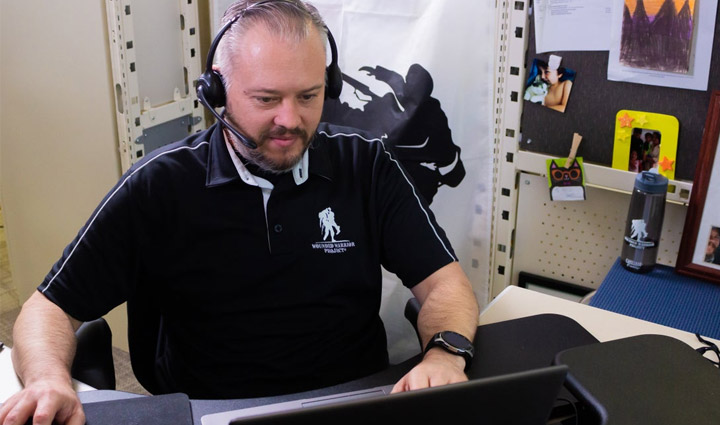 A WWP Resource Center teammate sits at his desk, attentively taking a call.
