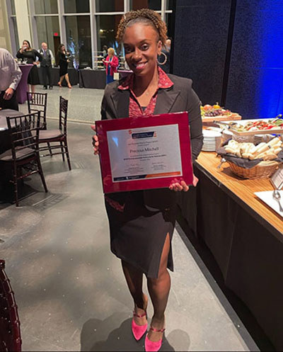 Air Force veteran Precious Mitchell holding a plaque from the Entrepreneurship Bootcamp for Veterans.