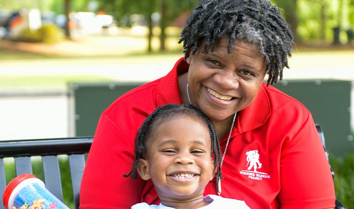La veterana herida Sam Hargrove sentada en un banco del parque abrazando a su nieto
