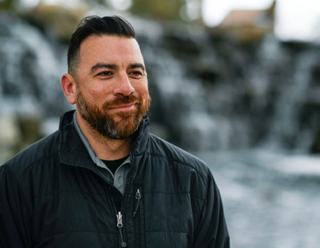 Wounded warrior Arnulfo Dauto smiling in front of a scenic background.