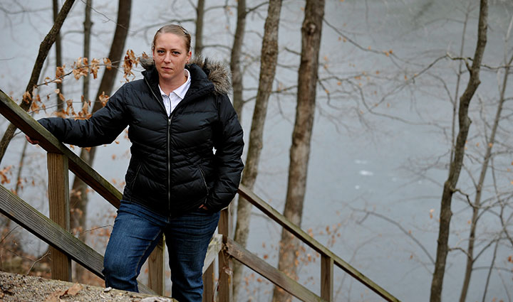 Wounded warrior Angie Peacock stands on a flight of stairs outside while resting her hand on the banister.