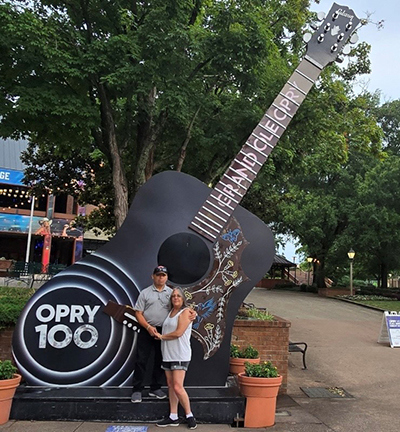Veteran Juan and his spouse Janet stand in front of a large guitar at the Grand Ole Opry.