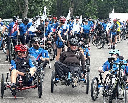 A large group of riders on bicycles and recumbent bikes gather and prepare to ride.