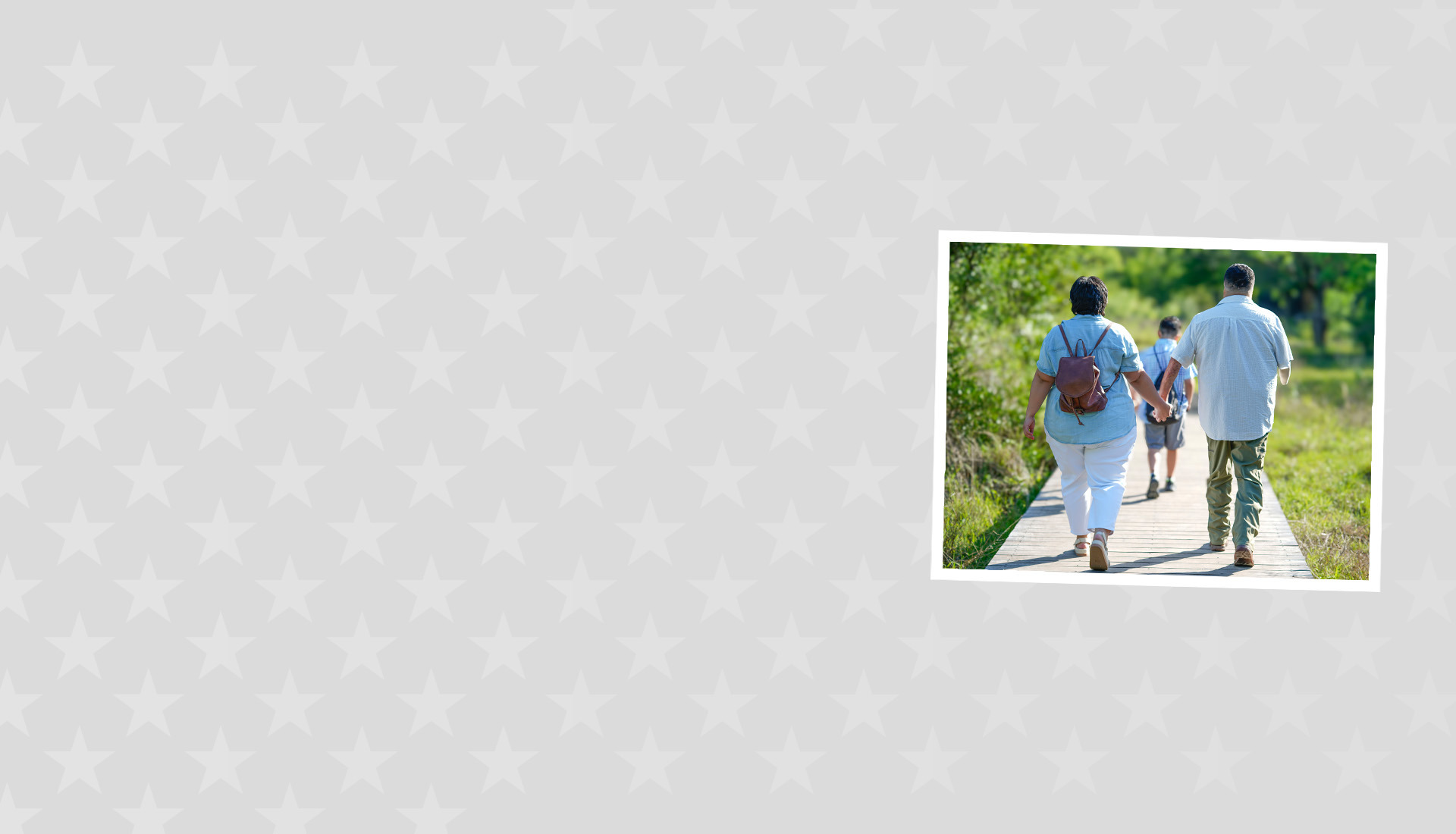 Warrior Anthony Villanueva walks hand in hand outdoors along a path with his wife, facing away from the viewer, with their son walking in front of them.