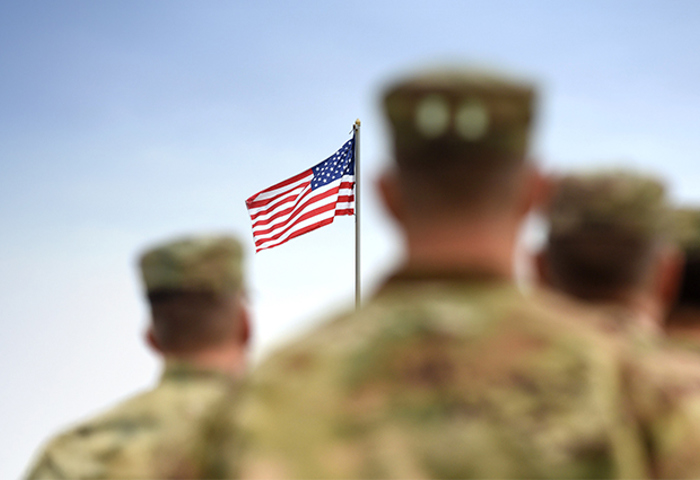 Soldiers standing together looking at the American Flag.