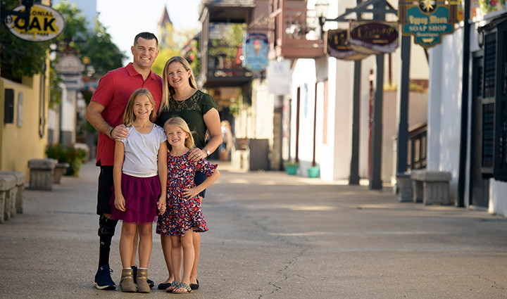 El guerrero herido Mike Larson y su familia posando para una foto en la calle.