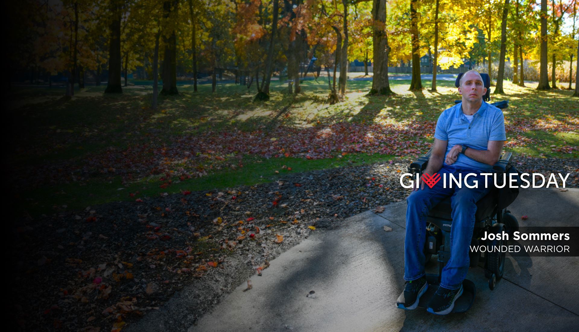 Wounded warrior Josh Sommers sits in his wheelchair in front of autumn leaves. He is looking at camera with serious face.
