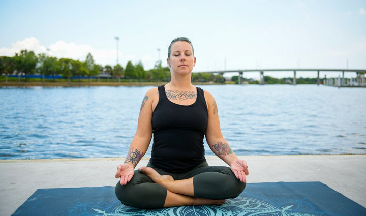 Wounded Warrior Jessica Coulter sitting outside doing a yoga pose and meditating.