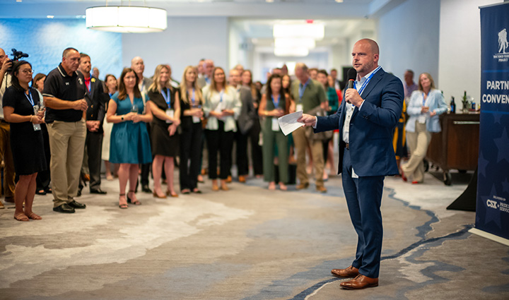 CSX’s Bryan Tucker wearing a suit speaking to a group of people at the WWP Community Partnerships & Investments Convening.