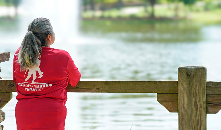 La veterana Maria Edwards de pie frente a una fuente de agua, de espaldas, con una camiseta roja de WWP.