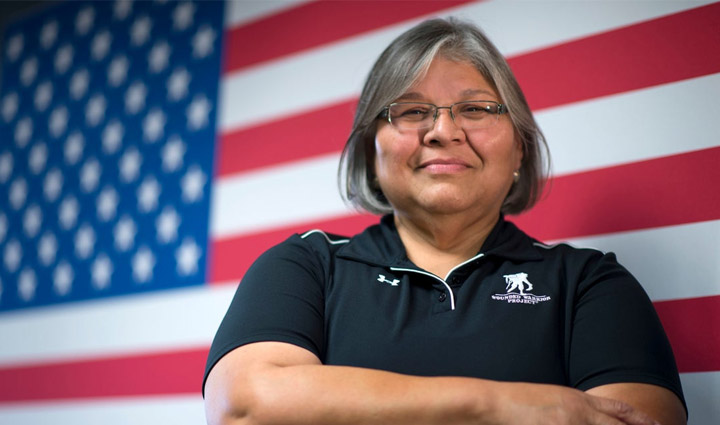 WWP teammate Mary Tallouzi stands in front of an American flag.