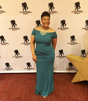 Wounded warrior TeakSafiya Wilson stands in front of a WWP step and repeat.