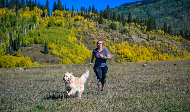 Wounded warrior Angie Peacock running in a field with her service dog.