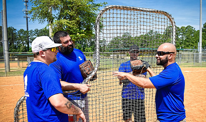 El veterano herido Carlos De Leon se para en un campo de béisbol con tres veteranos.