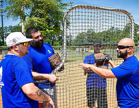 Warrior Carlos De Leon stands on a baseball field with three fellow warriors.