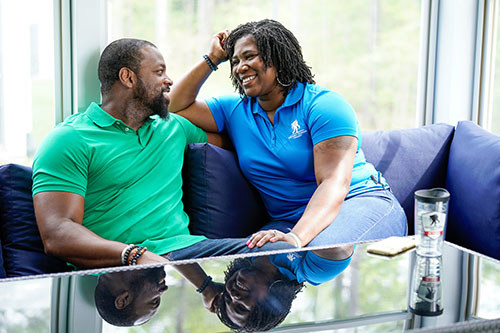 Veteran couple laugh with each other while sitting on the couch.