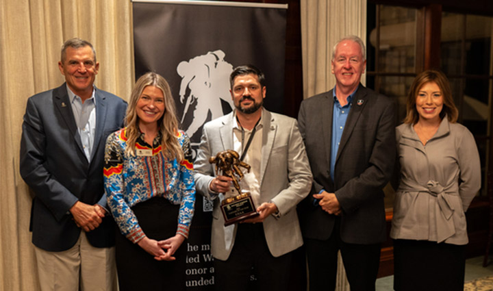 Former WWP CEO Mike Linnington, Jessie Carzoli, Chris Needles, and Brea Kratzert Todd from WWP stand with USAA representative Jody Revels, who is holding an award.