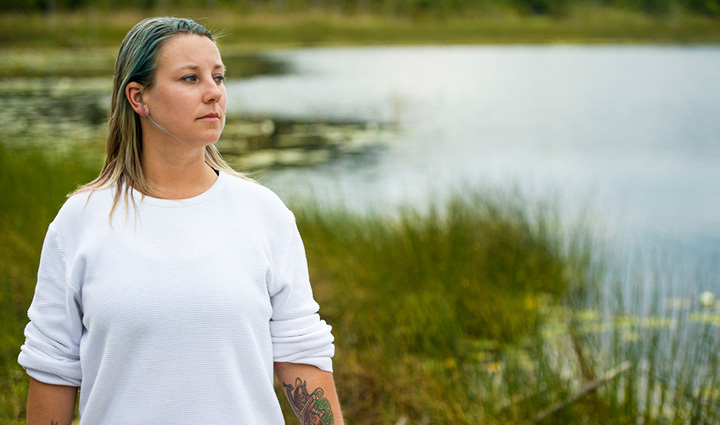 Warrior Jessica Coulter wearing a white sweater in front of a lake.