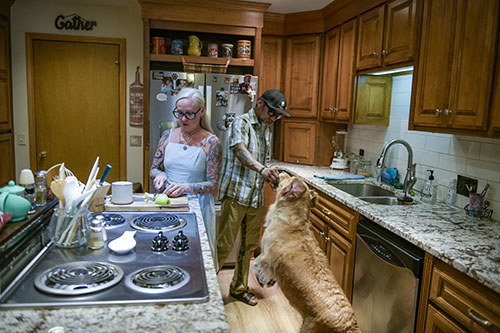 A warrior and his wife prepare dinner together as their dog gets some treats.