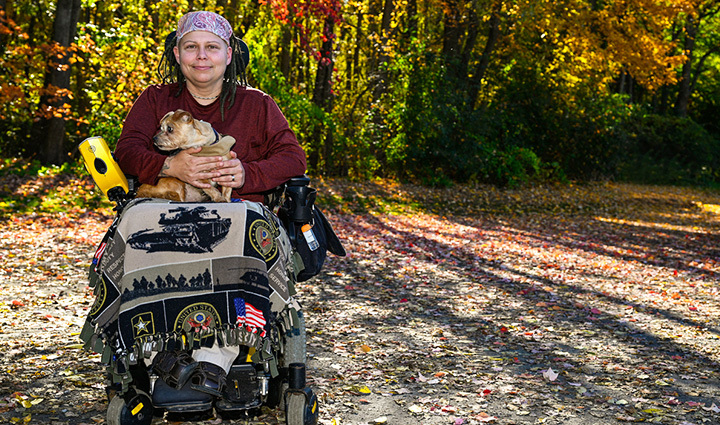Warrior Angie Lupe in a wheelchair holding a small dog.