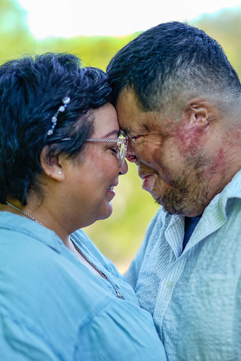 Wounded warrior Anthony Villareal stands with his wife, their foreheads touching. Both are smiling and wearing light blue shirts.