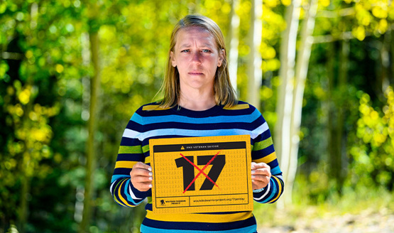 Warrior Angie Peacock wears a colorful shirt and holds a crossed-out 17 sign to support ending veteran suicide.