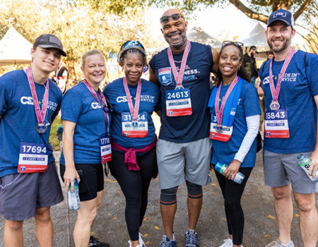 Three men and three women, all CSX employees, are dressed in blue t-shirts and standing together. They are smiling after completing the WWP Carry Forward 5K.