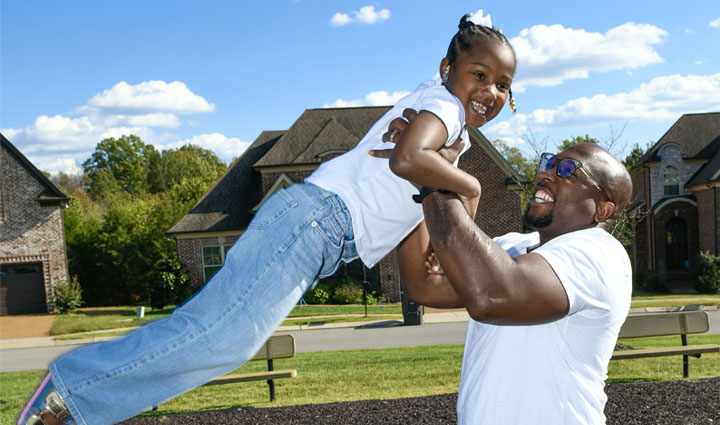 El veterano Melvin Gatewood sonríe y levanta a su hija.