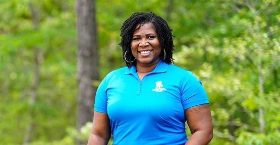 Taniki Richard, veterana herida, de pie al aire libre y sonriendo.