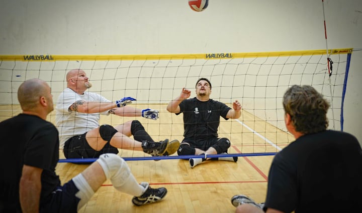 Los veteranos heridos Keith Sekora y Chris Wolff participan en un partido de vóleibol adaptado para veteranos con lesiones físicas.