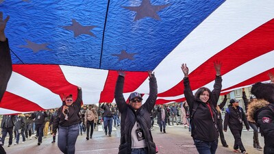 WWP warriors, veterans, and supporters hold up a flag while marching in the New York City Veterans Day parade.