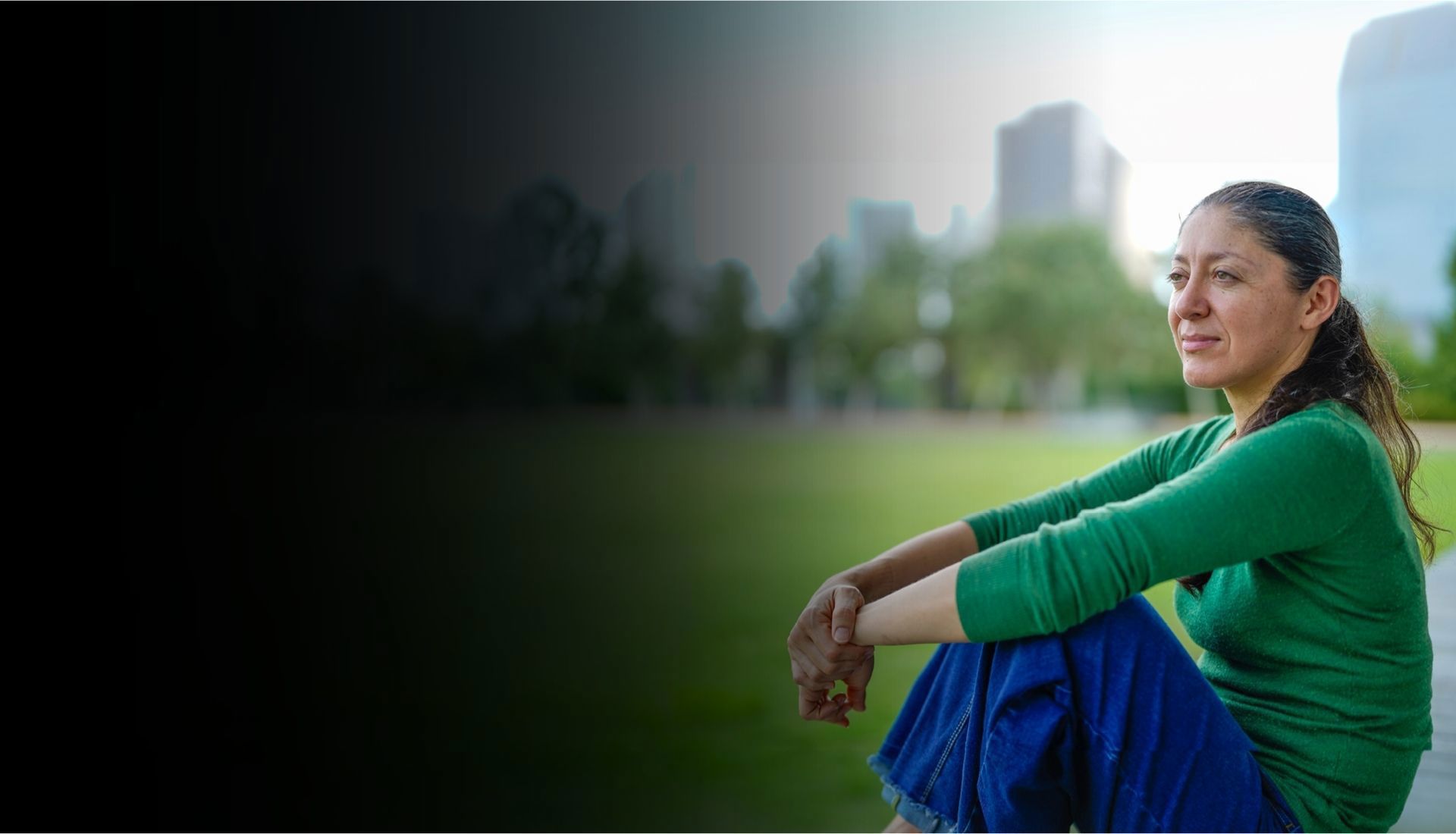 Warrior Ruth Corrigeux wears a green long sleeve shirt and jeans while sitting outside.