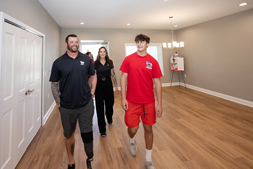Sean Karpf and his family stand smiling inside an empty room of his new home.