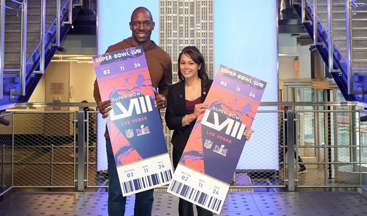 Wounded warrior Antoinette Wallace stands with retired New York Giants player Kevin Boothe holding two oversized Super Bowl tickets.