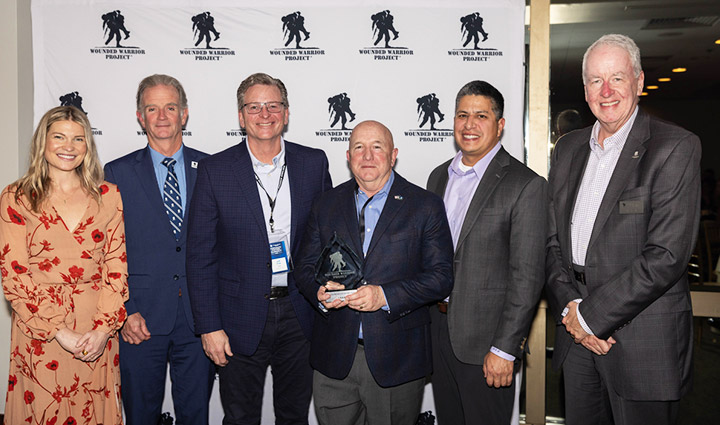 USAA executives Jeff Fink, Gino Montagno, and Chris Figueroa stand between WWP staff Jessie Carzoli, CEO Walt Piatt on the left and Chief Chris Needles on the right.