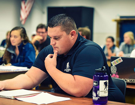 Warrior Brian Wagner sits at a table while looking at a notebook in front of him.