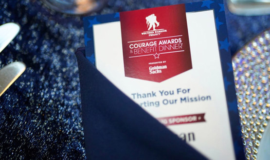 El programa de Courage Awards and Benefit Dinner colocado sobre un mantel azul brillante.