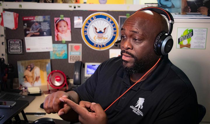 Un miembro del equipo de Wounded Warrior Project sentado en su escritorio, usando un auricular y hablando con un veterano inscrito en el programa Talk de WWP.