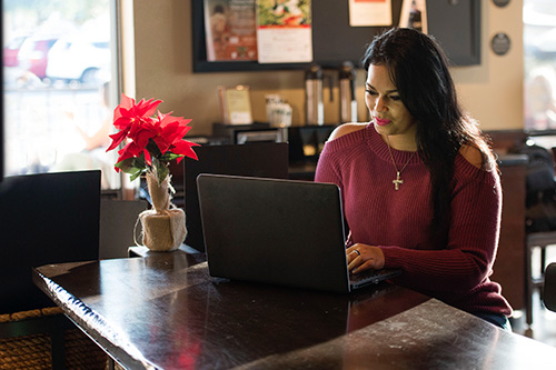 La veterana herida Yomari Cruz sentada a una mesa mientras escribe en una laptop.