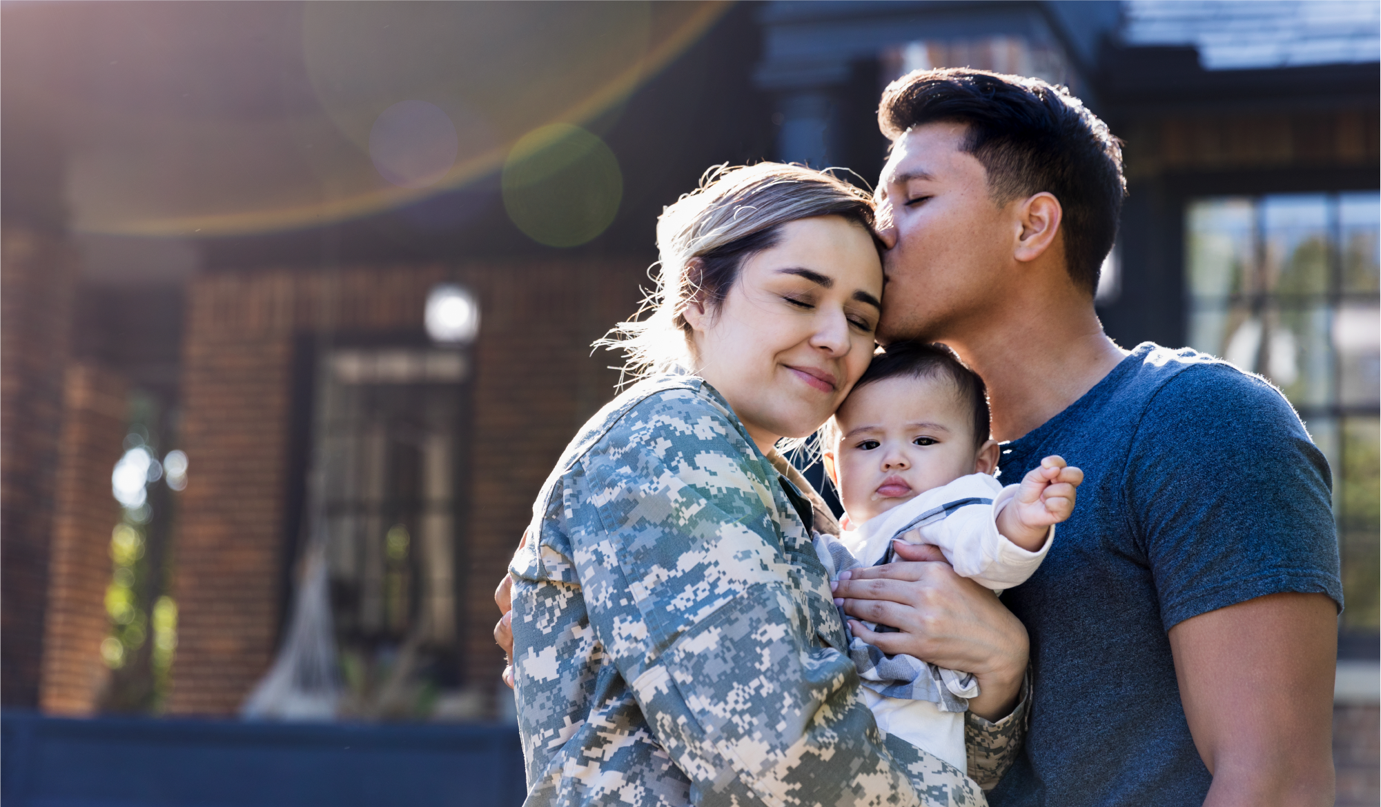 Una veterana herida sostiene a su bebé mientras posa para una fotografía junto a su esposo.
