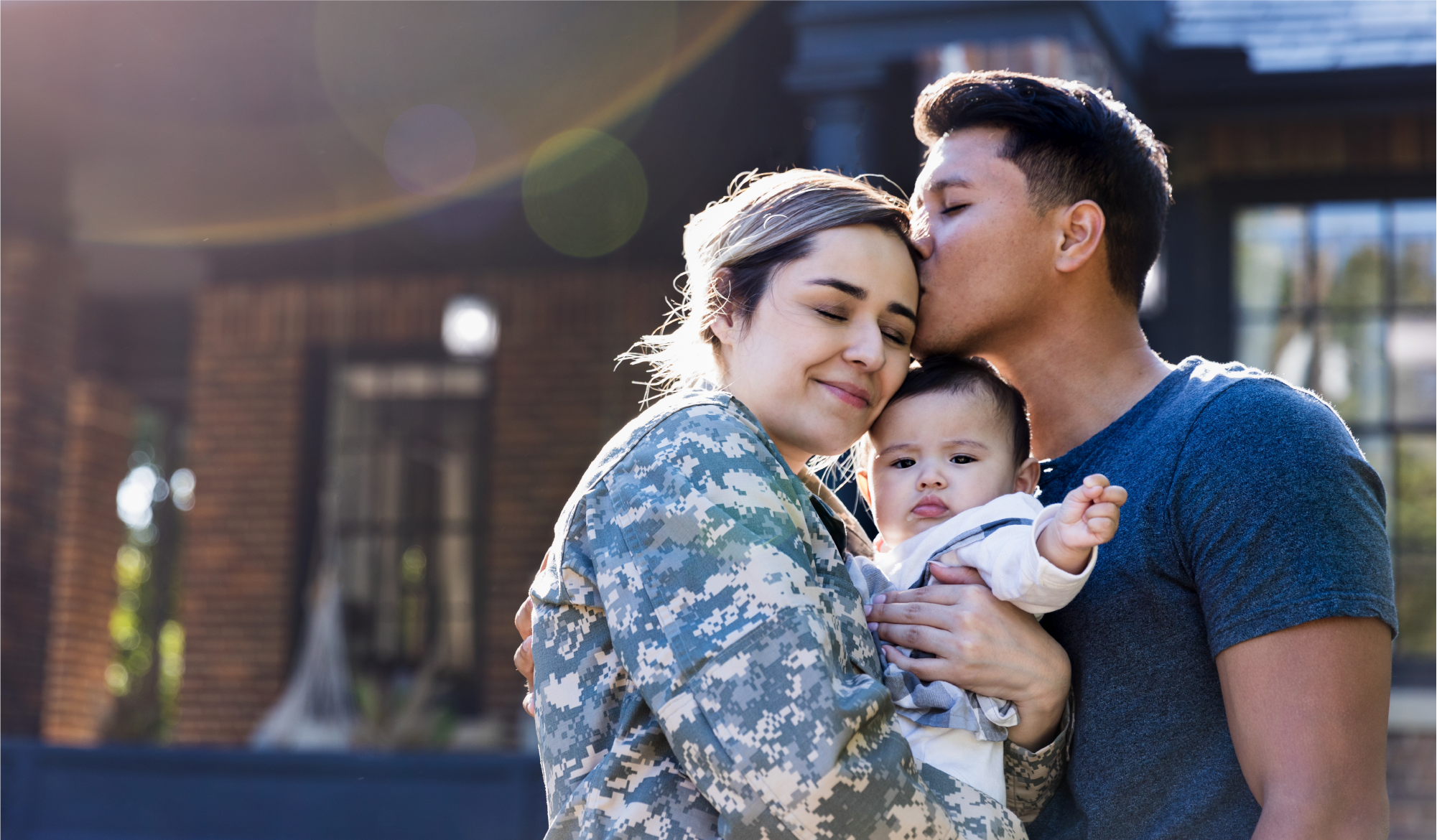 A wounded warrior holds her baby while posing for a photo with her husband.