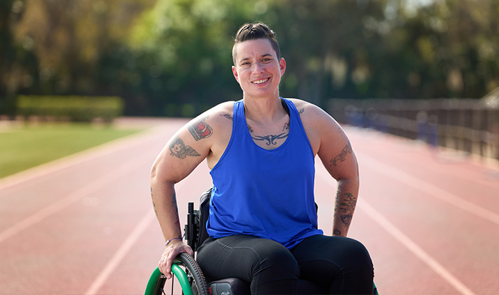 Wounded warrior Beth King sits in a wheelchair on a running track. 
