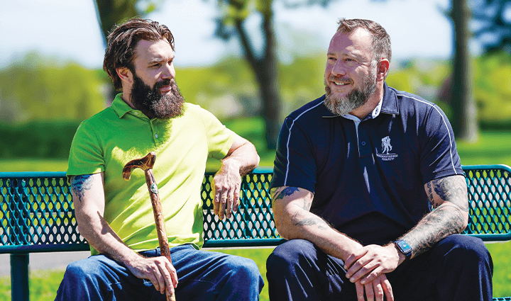 WWP warriors Drew Carpenter and Anthony Craiden sit on a park bench talking.