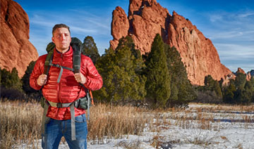 Man with a backpack standing in front of a mountain