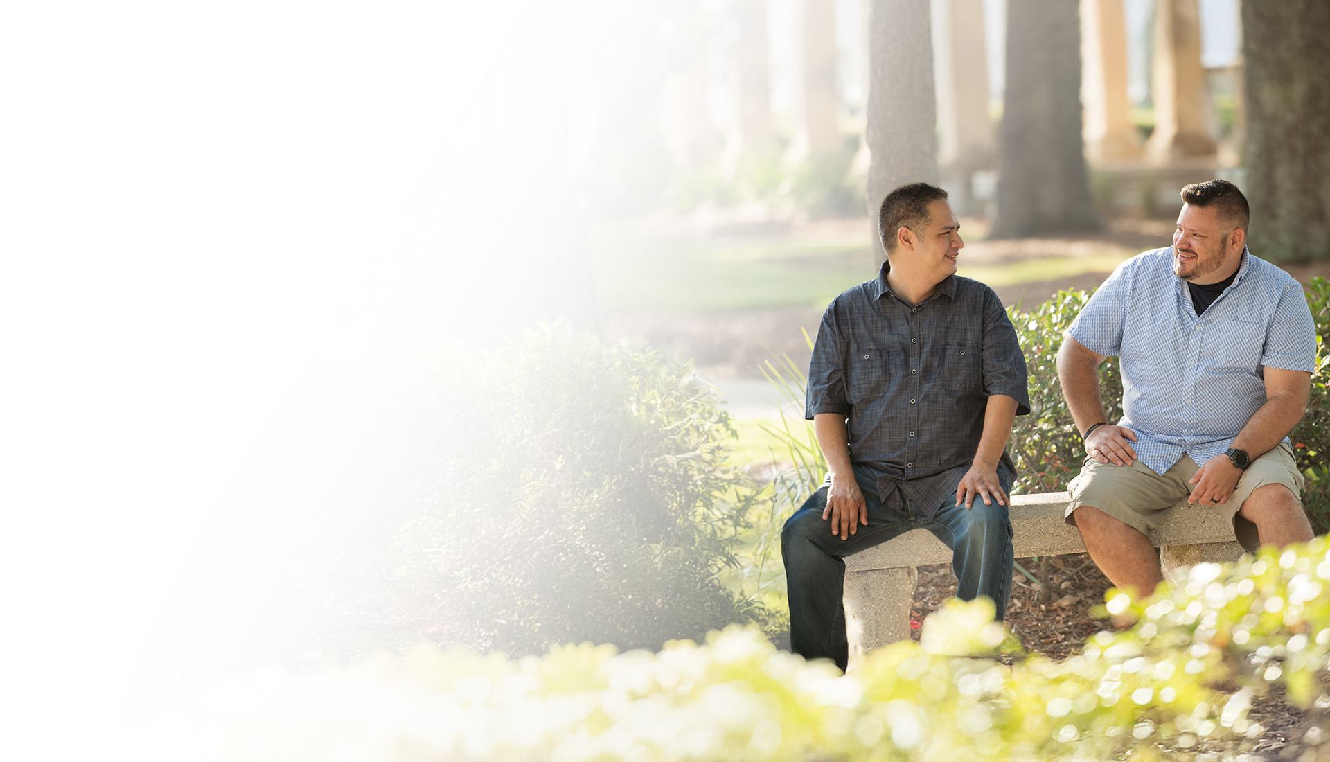 Wounded warriors Jason Major and Jacob Norotsky sit outside on a bench smiling and talking to each other.