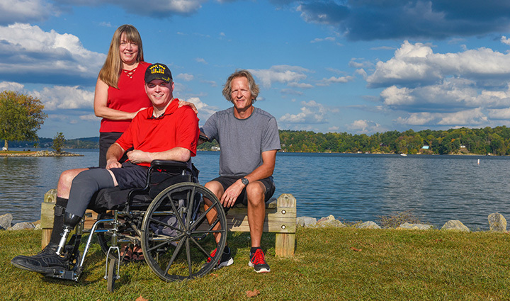 Warrior Jason Ehrhart sitting outside in a wheelchair with his parents.