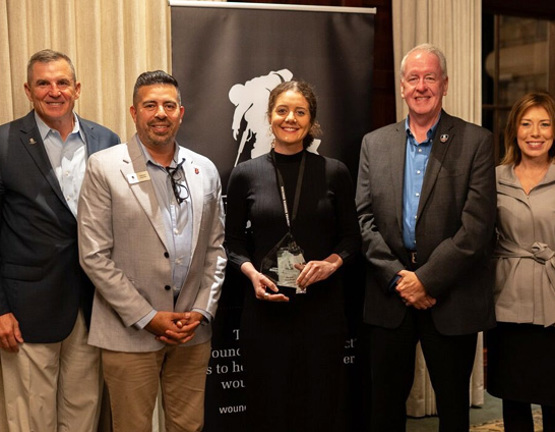 The NFL’s Megan Mendoza holds an award from executives Mike Linnington, Helbert Asprilla, Chris Needles, and Brea Kratzert.