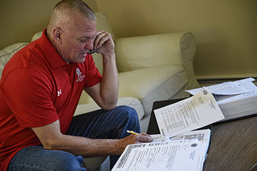 El veterano herido Tom Kowolenko lee algunos documentos mientras habla por teléfono.