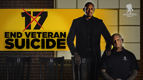 Two warriors sit on chairs with a sign that has the number 17 crossed out.